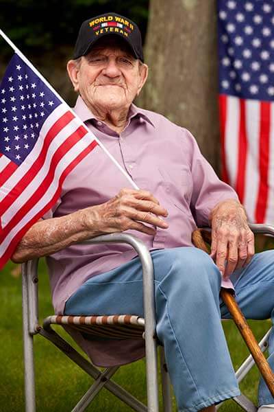 elderly male WWII veteran holding an American flag