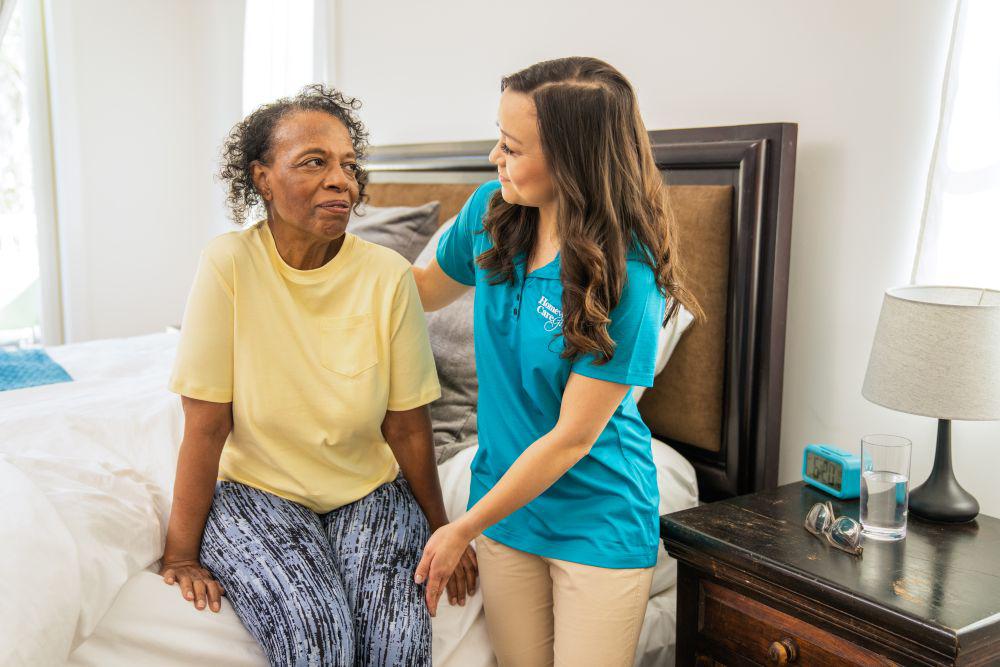 A female caregiver helps a senior woman out of bed