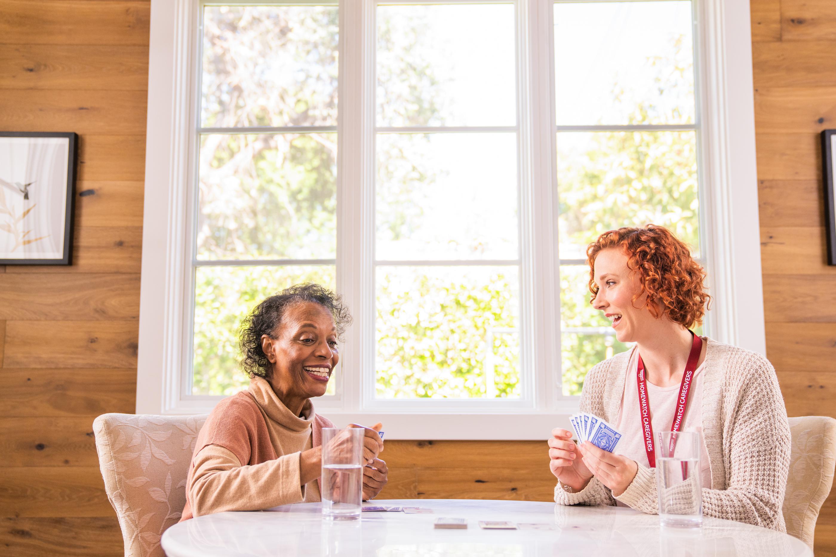 Homewatch caregiver playing cards with elderly woman