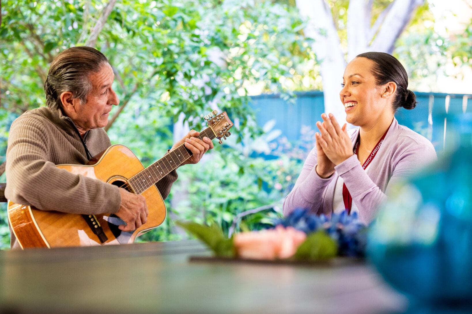 man playing guitar and woman listening