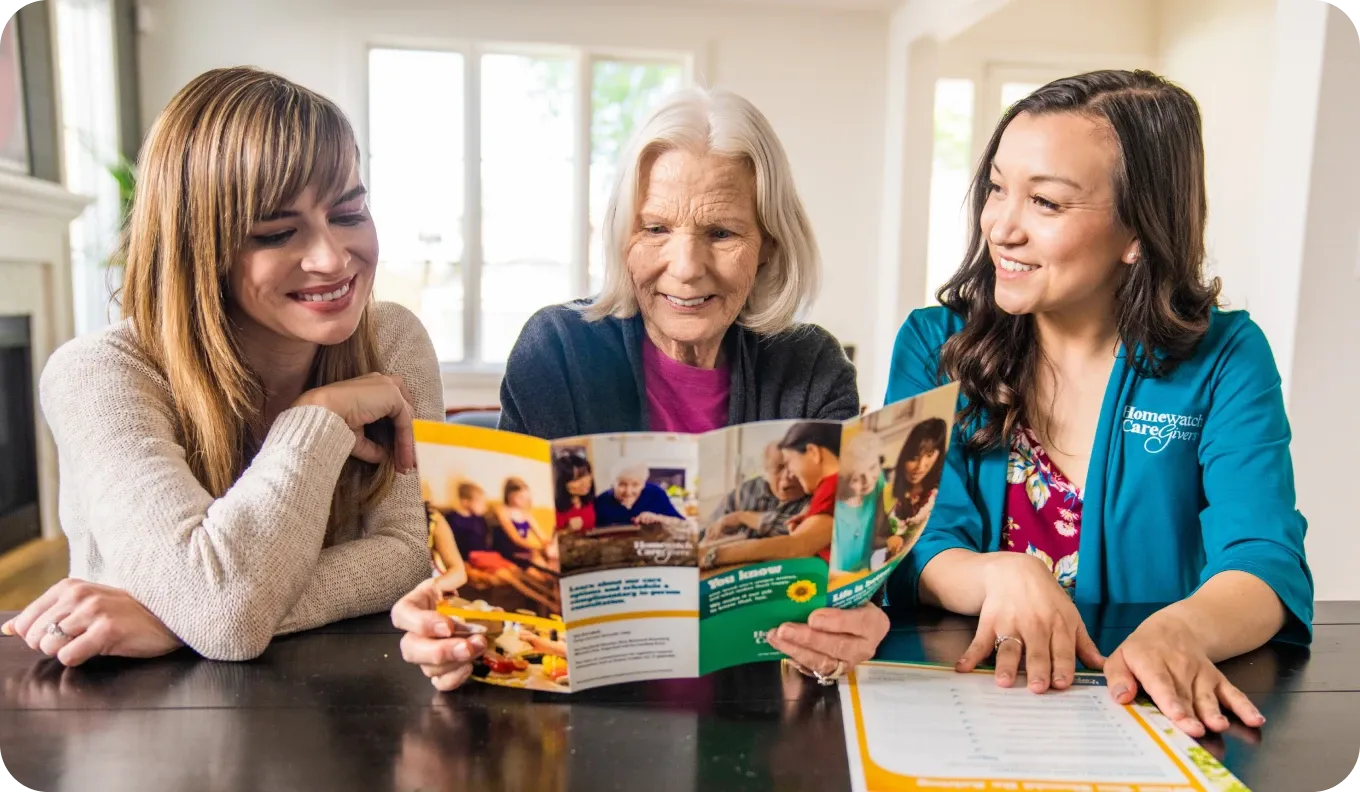 Woman and her mother reading a pamphlet with a caregiver