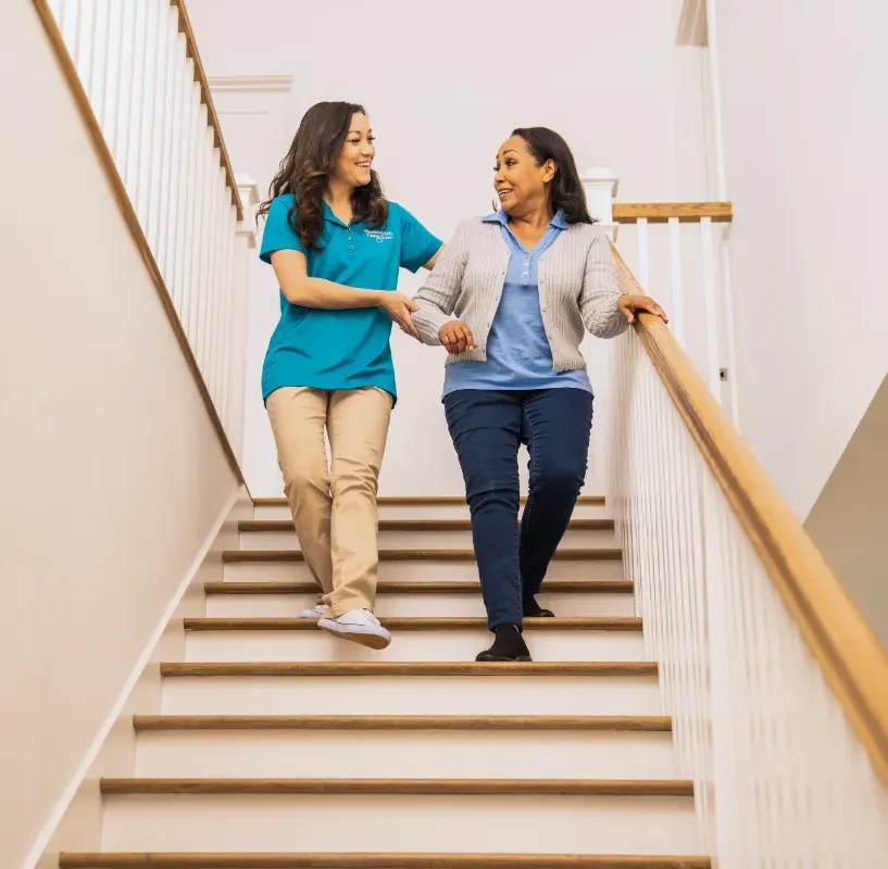 An aid helping woman walk down stairs