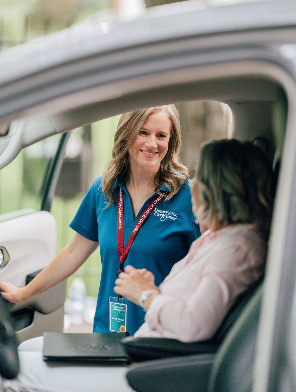 female caregiver helping senior woman out of car