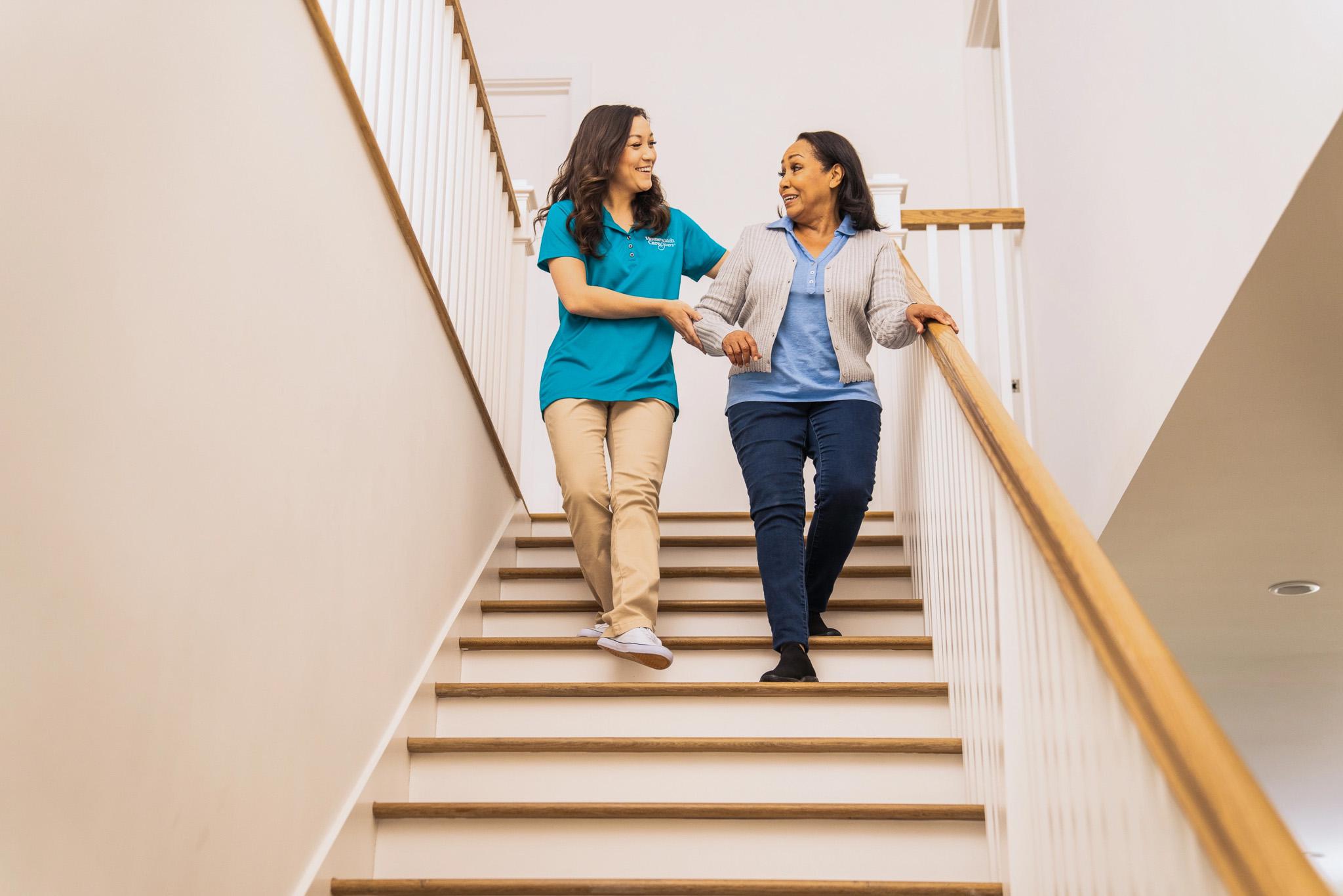 A caregiver helping a patient walk down the stairs
