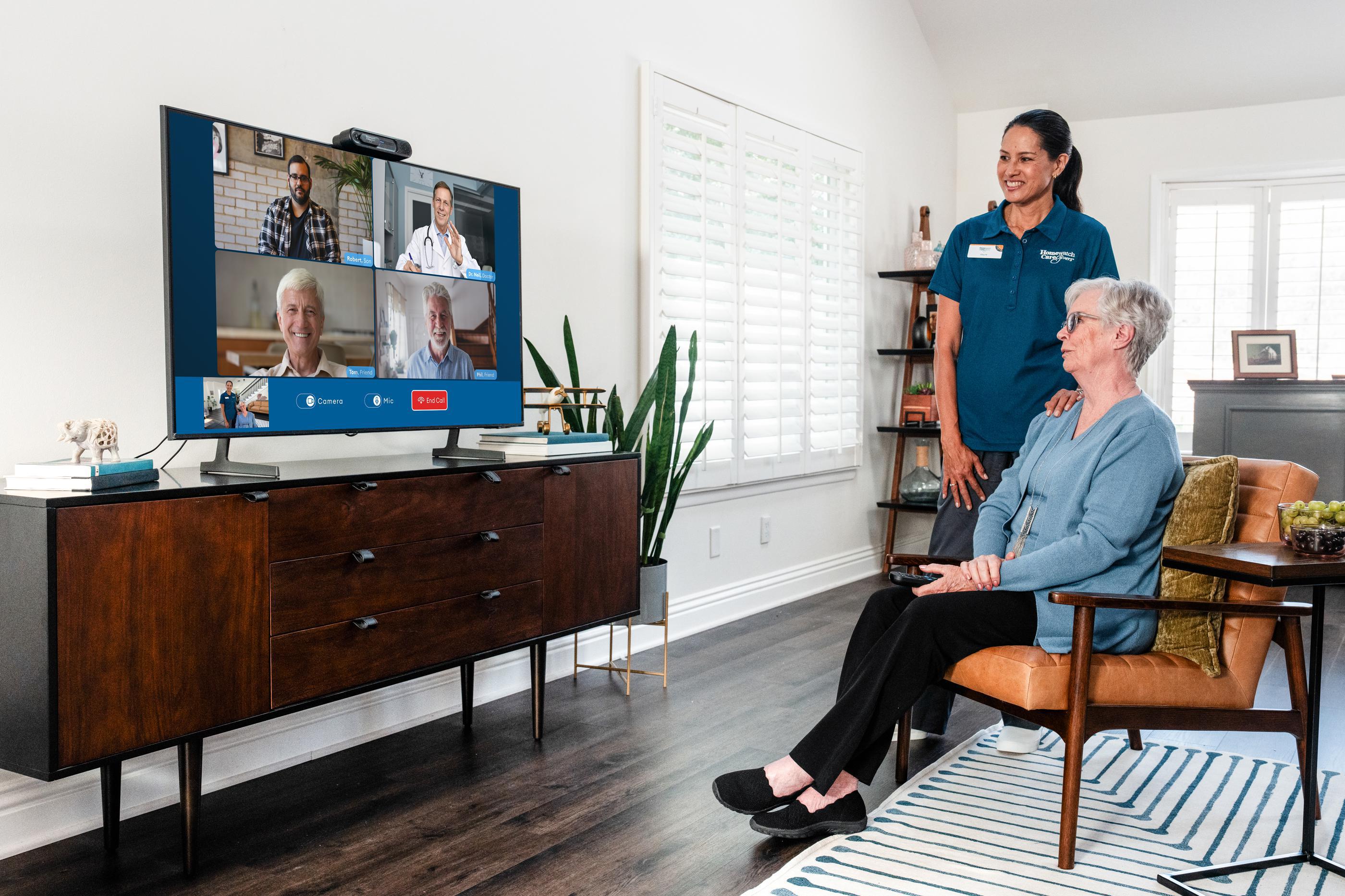 older woman watching tv with care worker behind her