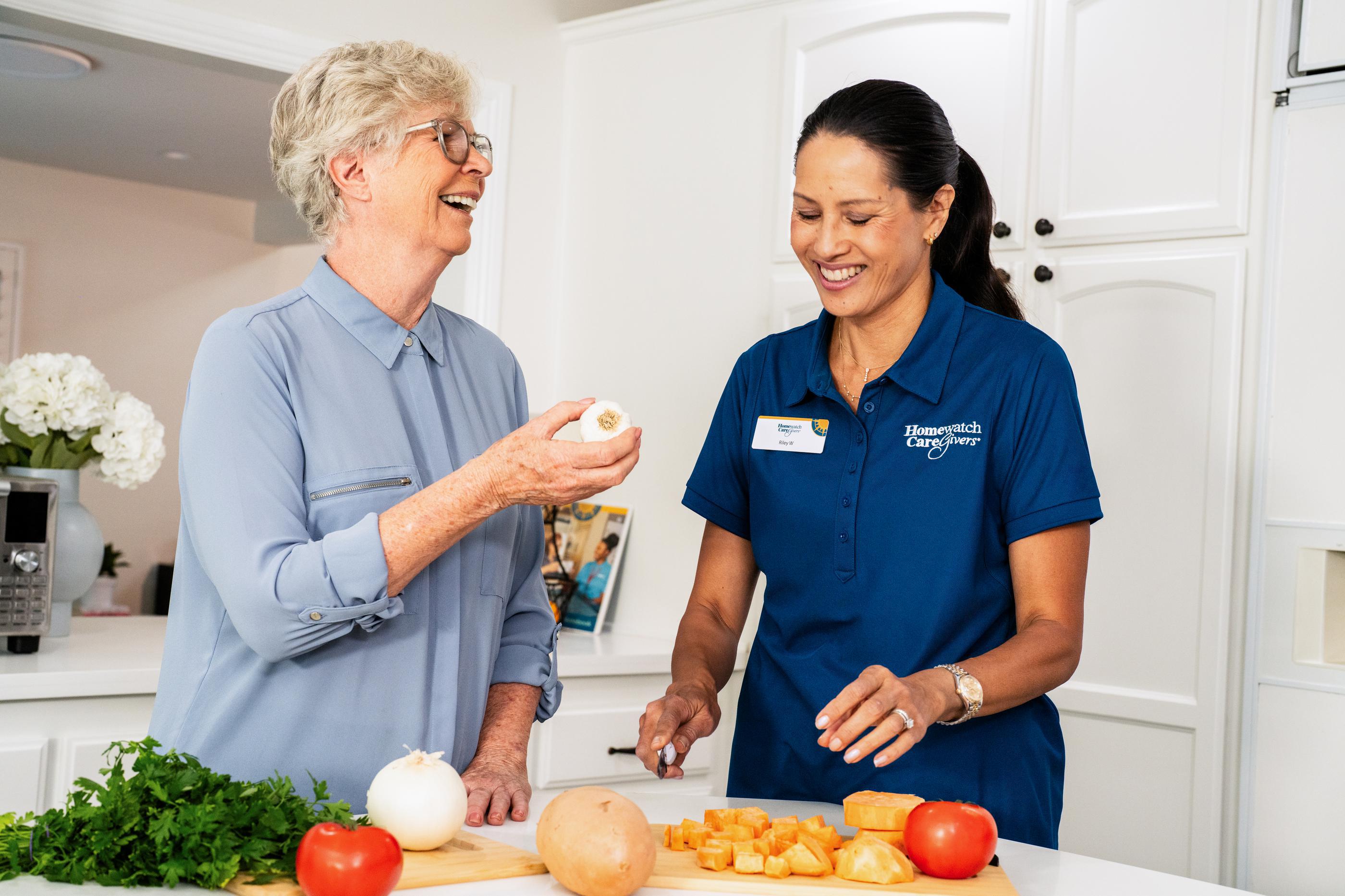two woman standing in kitchen next to vegetables