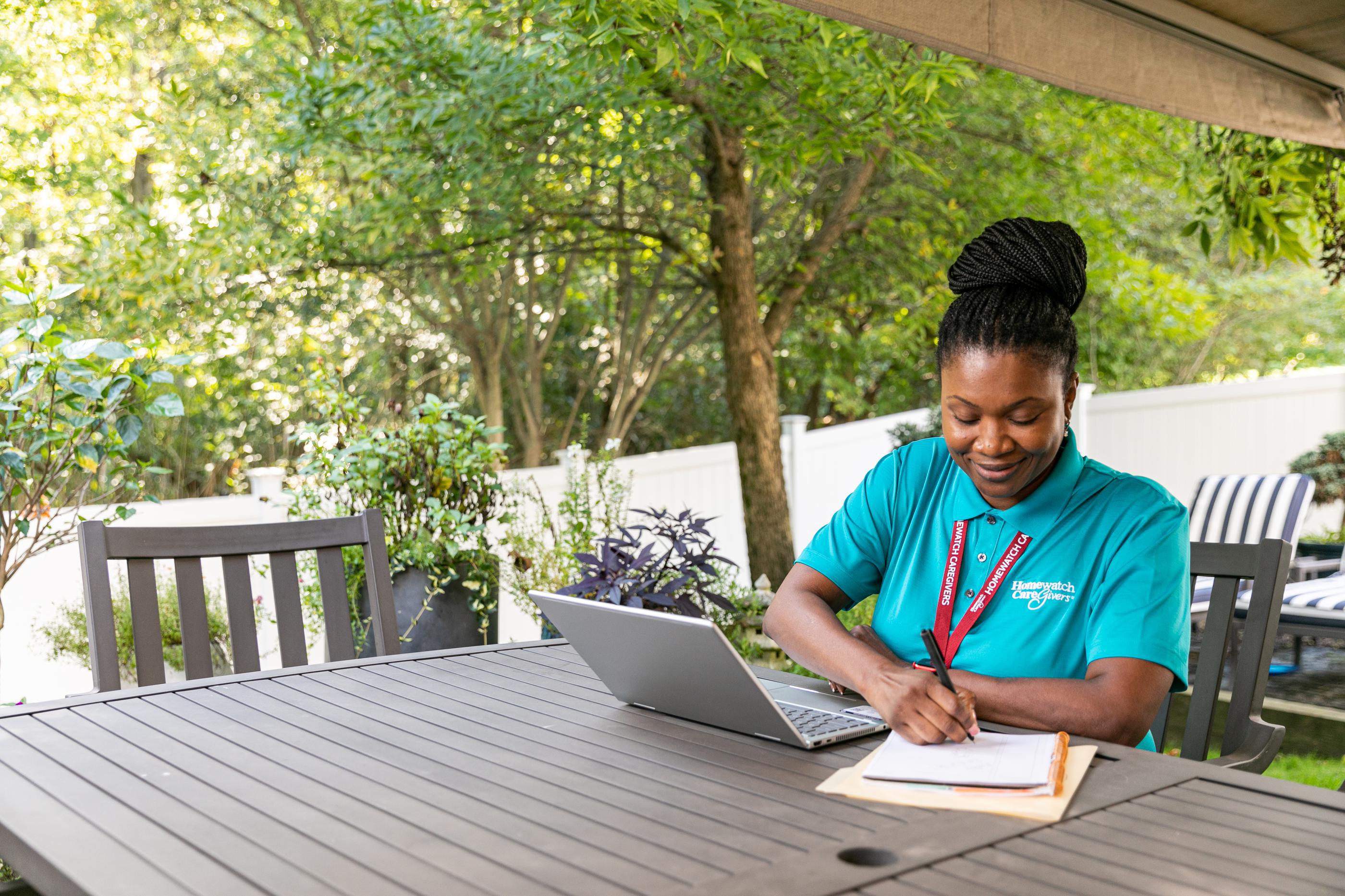 Caregiver sitting outside at table writing