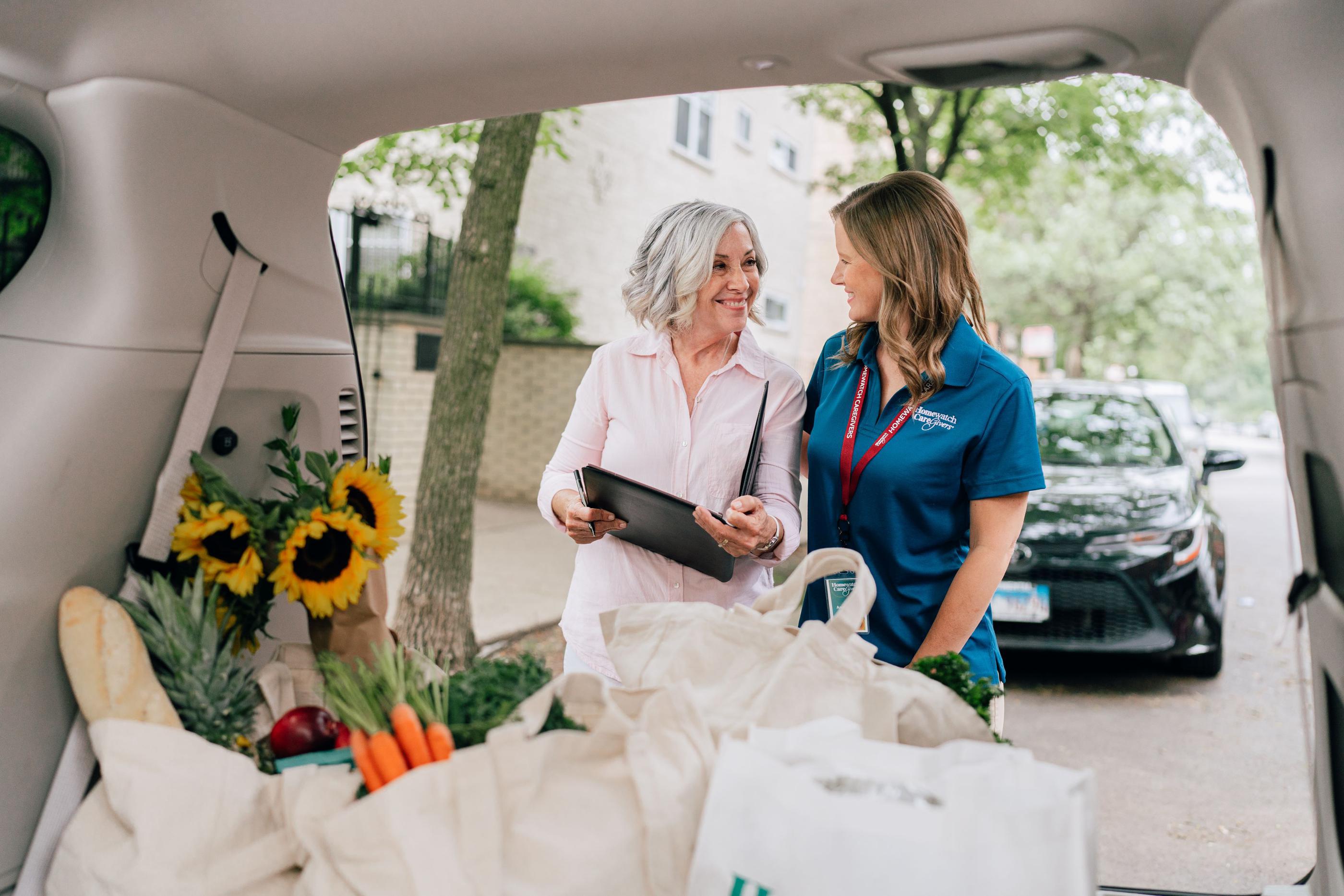 woman and caregiver standing next to open car trunk