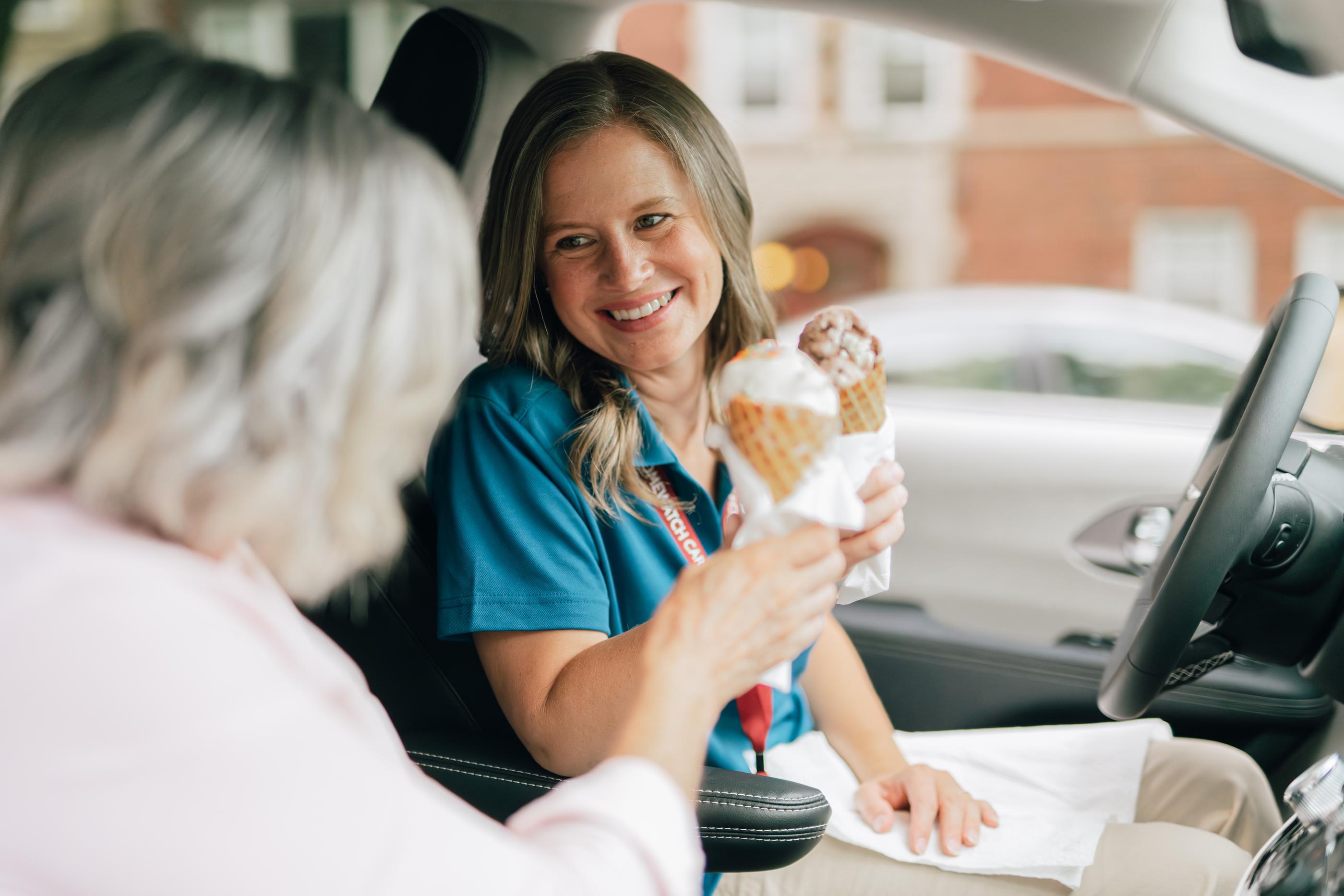 Woman sitting in car holding ice cream and smiling