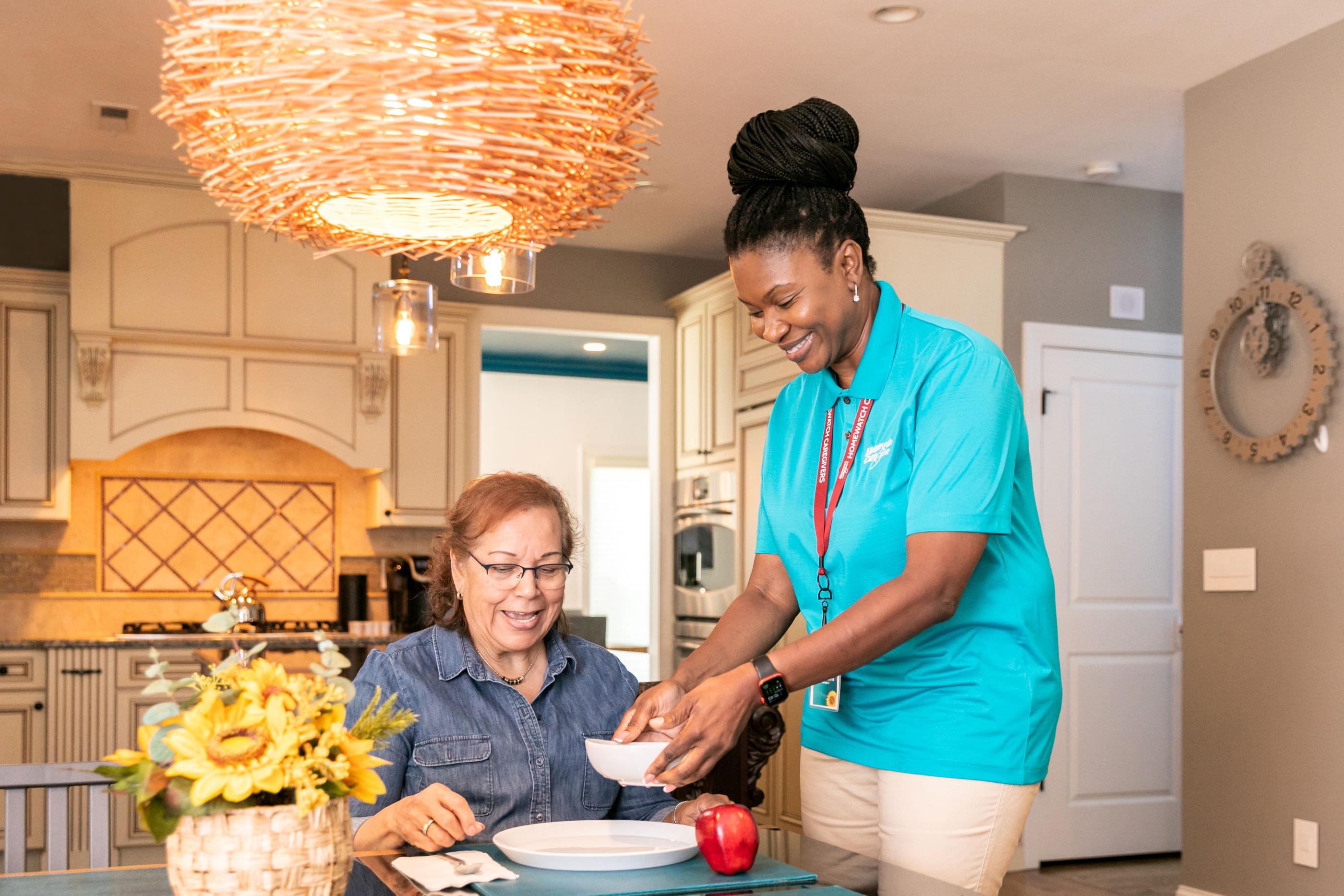 caregiver giving woman food at table