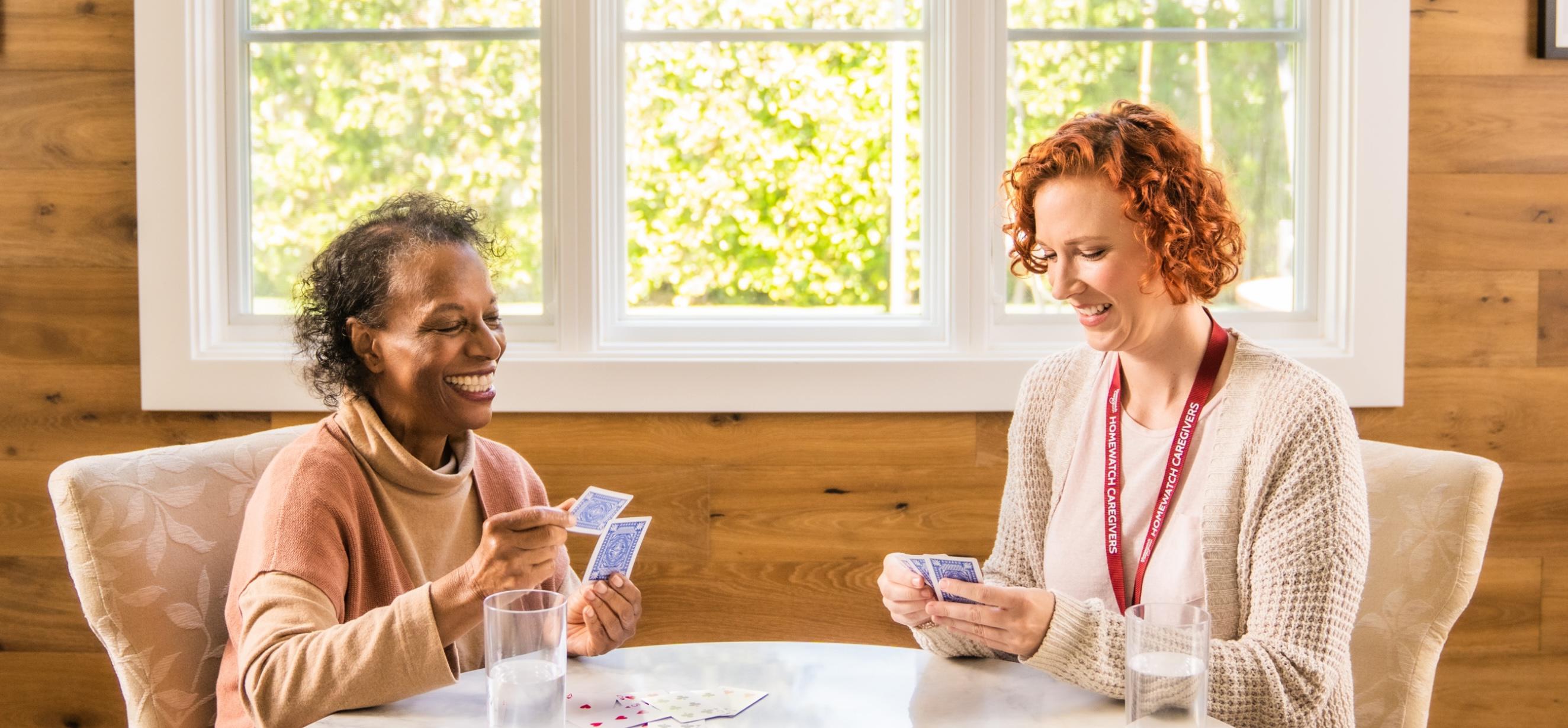 A caregiver playing cards with an elderly woman.