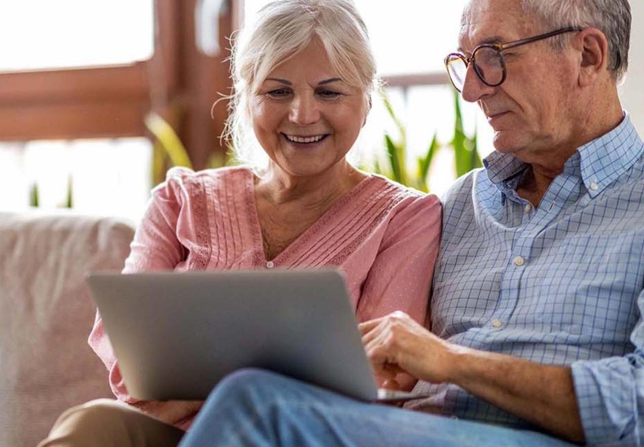 couple sitting on couch look at laptop