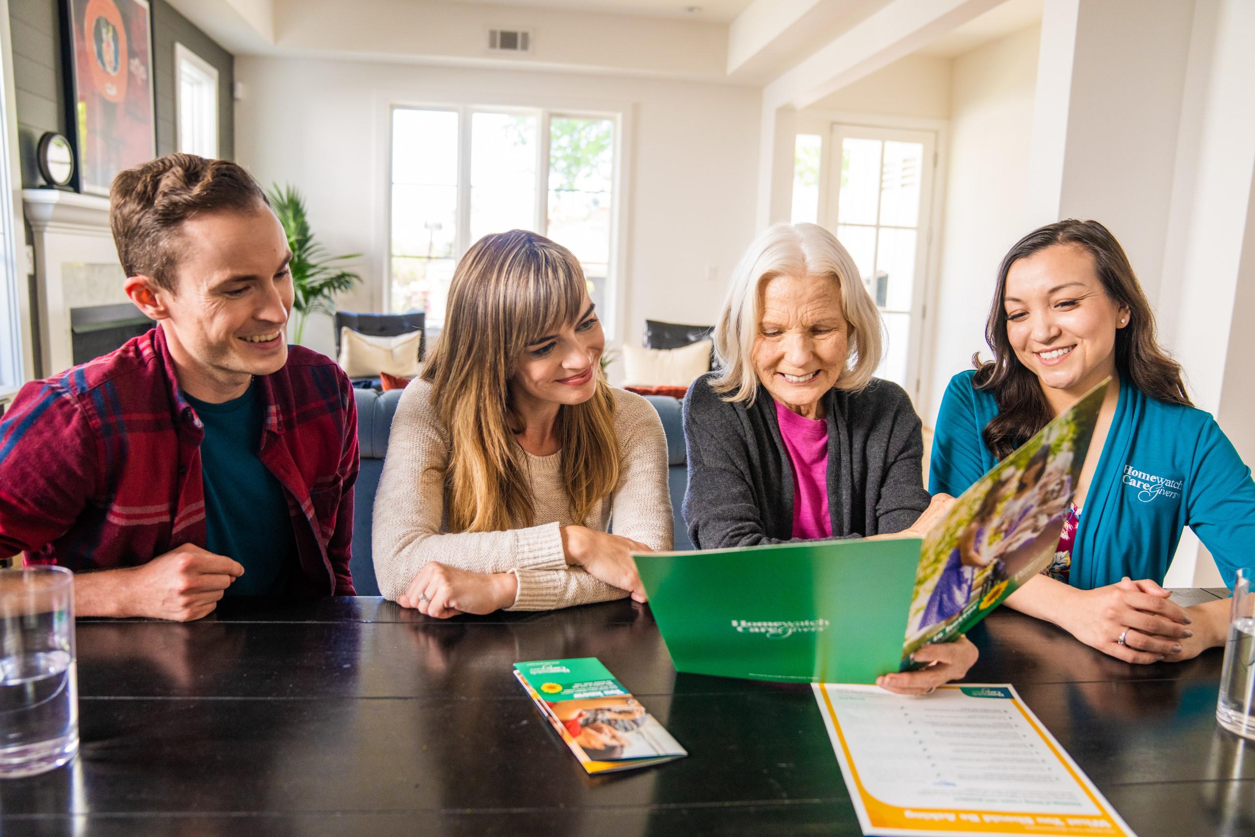 adult children with elderly mother looking at homewatch caregivers brochure