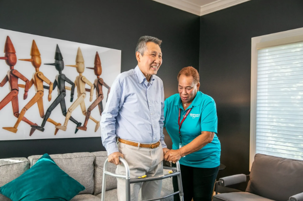 man standing with walker while woman helps him
