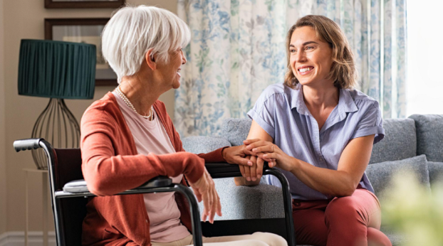 woman smiling and holding woman's hand in wheelchair