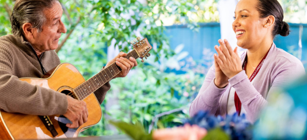 man playing guitar while woman claps