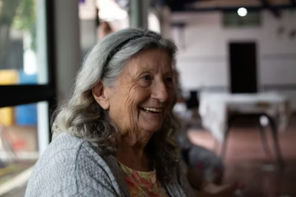 woman with long gray hair smiling away from camera