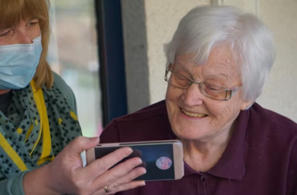 woman with mask holding phone up to woman smiling