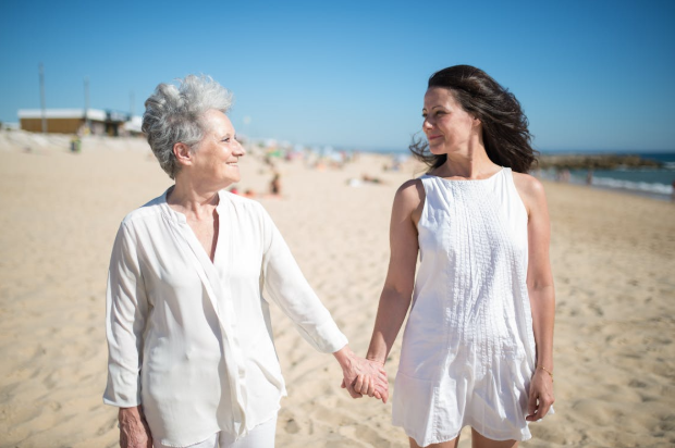 two women at beach smiling and holding hands