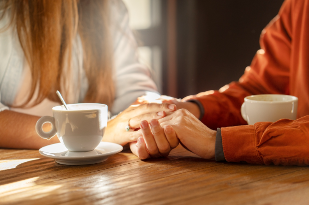 hands holding on a table next to coffee cups
