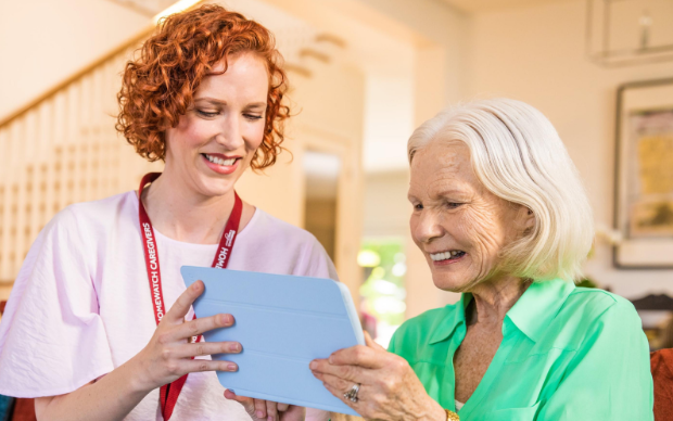 home care professional and woman smiling and looking at tablet