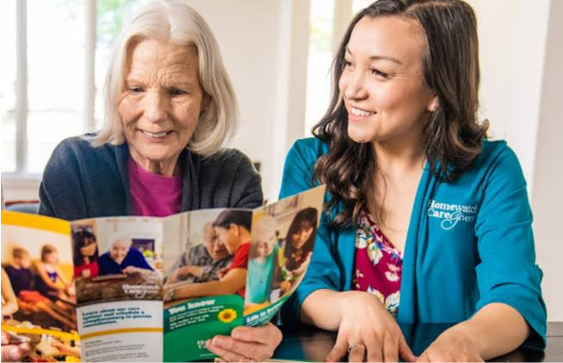 health care professional sitting next to woman looking at brochure