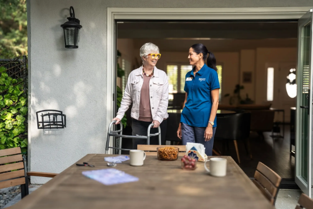 woman with walker walking onto patio with caregiver