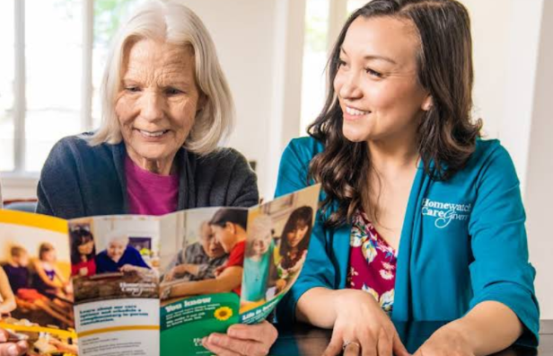 woman and caregiver looking at Homewatch CareGivers brochure