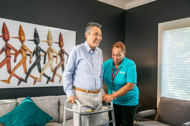 man standing up with walker next to caregiver