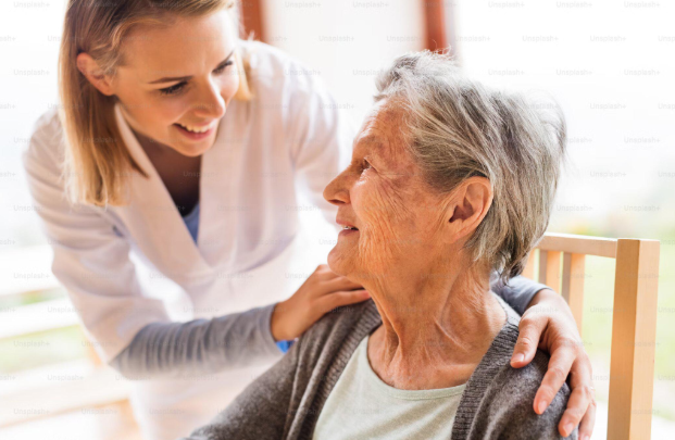 caregiver smiling and holding woman's shoulders