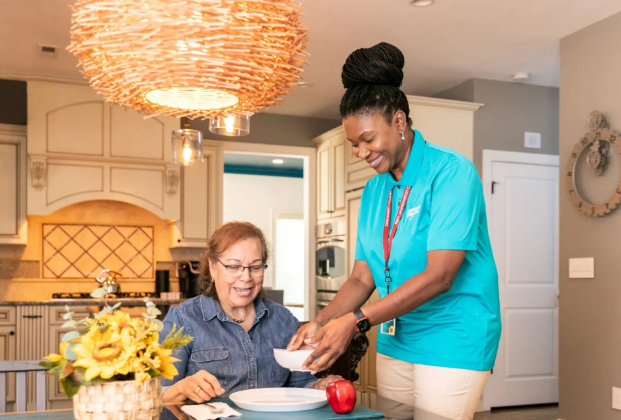 Caregiver smiling with woman in kitchen