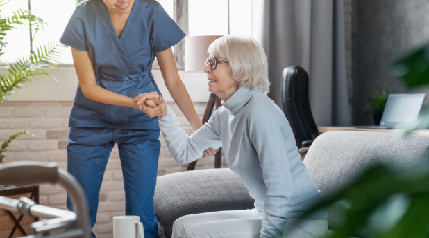 caregiver helping woman off couch