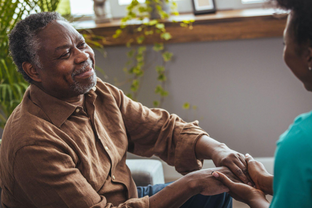 man smiling and holding hands with caregiver