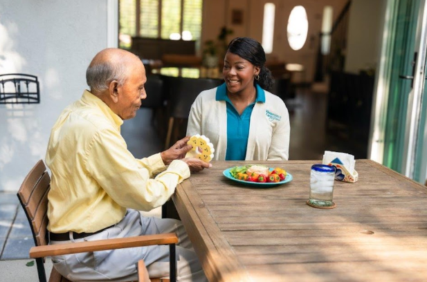 man taking pills out of container with caregiver smiling