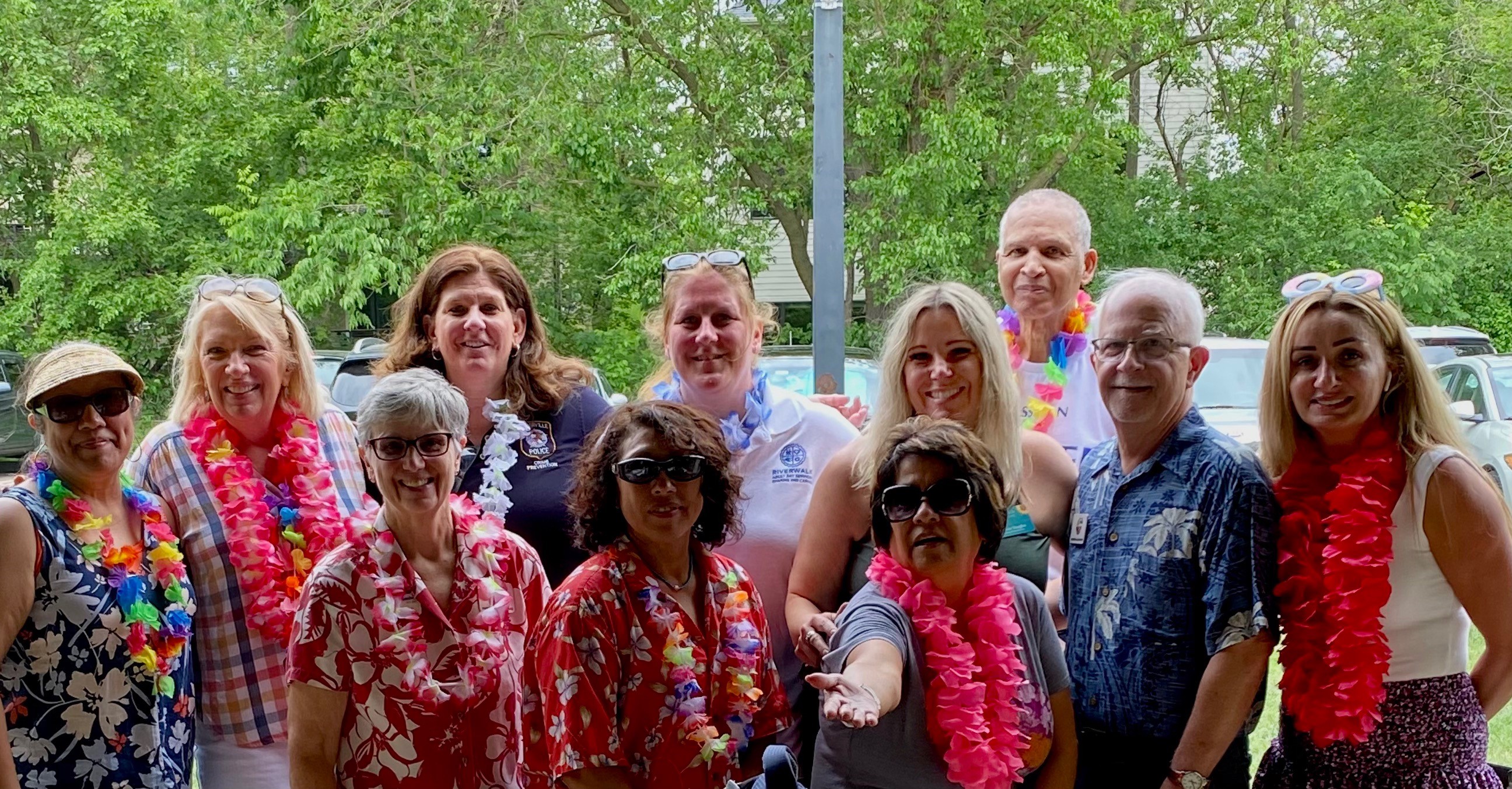 Image og group of people smiling wearing Hawaiian style clothing